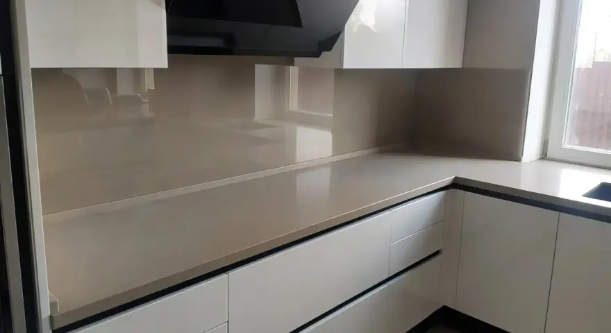 Nowoczesna kuchnia z frontami w kolorze ral9001 i eleganckim, jasnym blatem. Czarny okap dodaje charakteru.