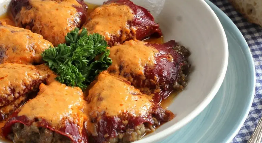 Pimientos rellenos de carne, cubiertos con una cremosa salsa y adornados con perejil fresco. Un plato casero listo para disfrutar.