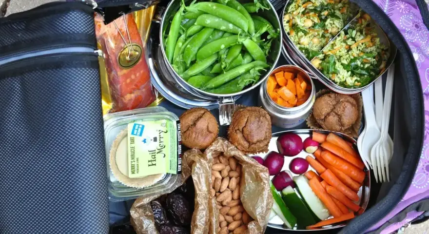 Idealne jedzenie do samolotu: fasolka, sałatka, marchewka, migdały, daktyle, muffiny, wędzony łosoś i tartaletka.