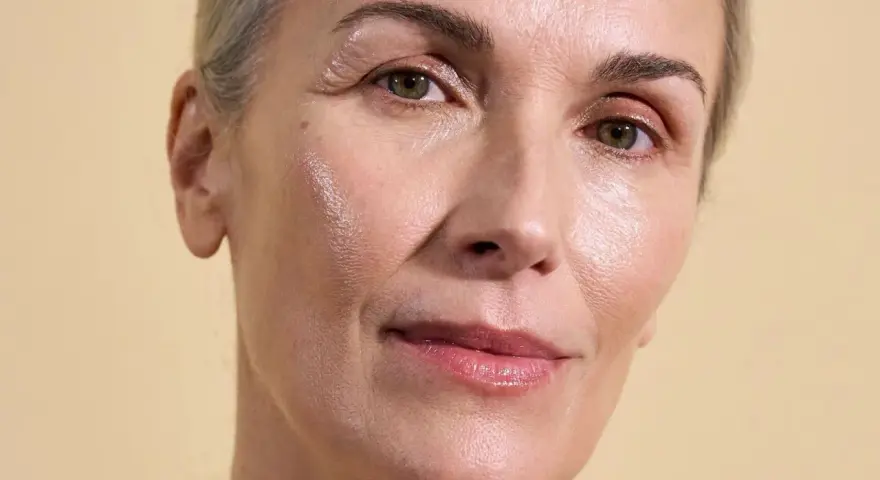 Visage d'une femme aux cheveux gris, peau lumineuse et hydratée, suggérant l'efficacité des peptides pour une peau éclatante.