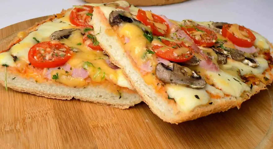 Dwie pyszne pizze na bagietce z pomidorami, pieczarkami i serem. Idealne na szybki obiad.