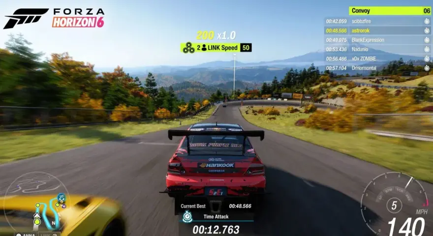 Wyścig w Forza Horizon 6 na PS5. Czerwony samochód pędzi po krętej drodze wśród jesiennych drzew.