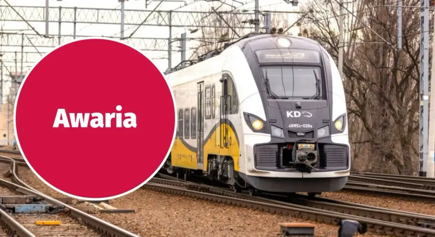 Pociąg KD stoi na torach, a czerwone koło z napisem "Awaria" sugeruje problem z zasilaniem, być może zerwana sieć trakcyjna.