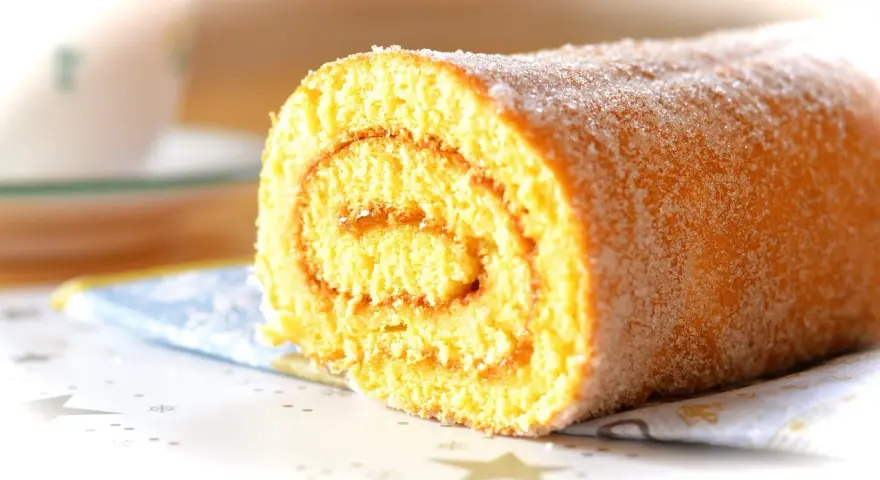En saftig glutenfri rulltårta med socker strött över, perfekt för fikat.