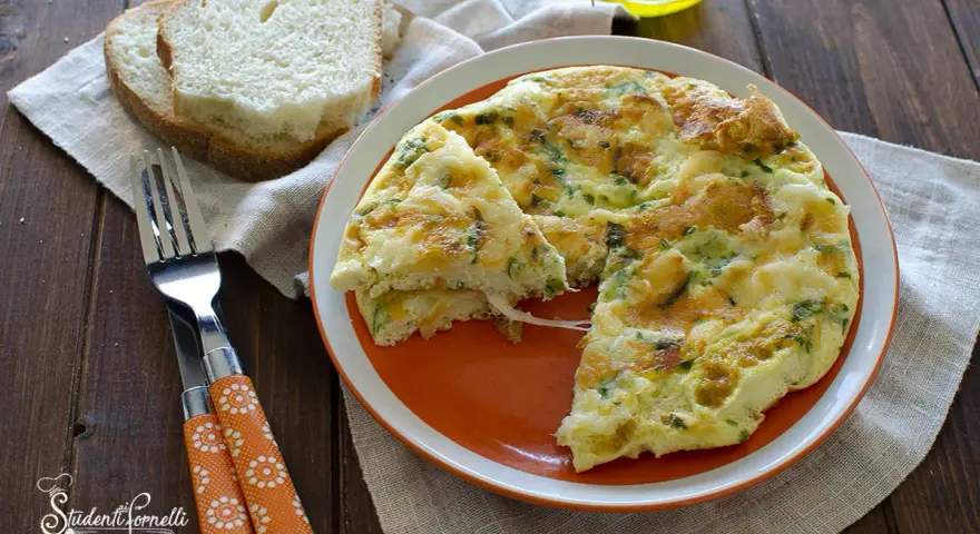 Una soffice frittata di albumi con erbe aromatiche, servita su un piatto arancione, accanto a fette di pane tostato e una forchetta.