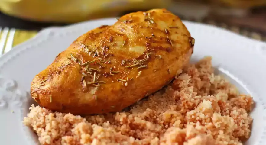 Deliziosi fusi di pollo in friggitrice ad aria, dorati e profumati al rosmarino, serviti su un letto di couscous.