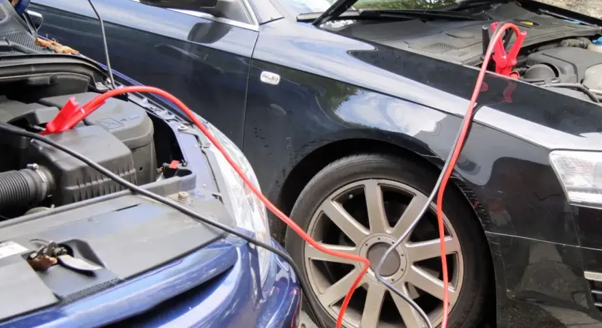 Zwei Autos werden mit Starthilfekabeln verbunden, um die Batterie zu starten.
