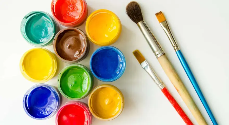 Tarros de temperas de colores vibrantes y pinceles listos para pintar.