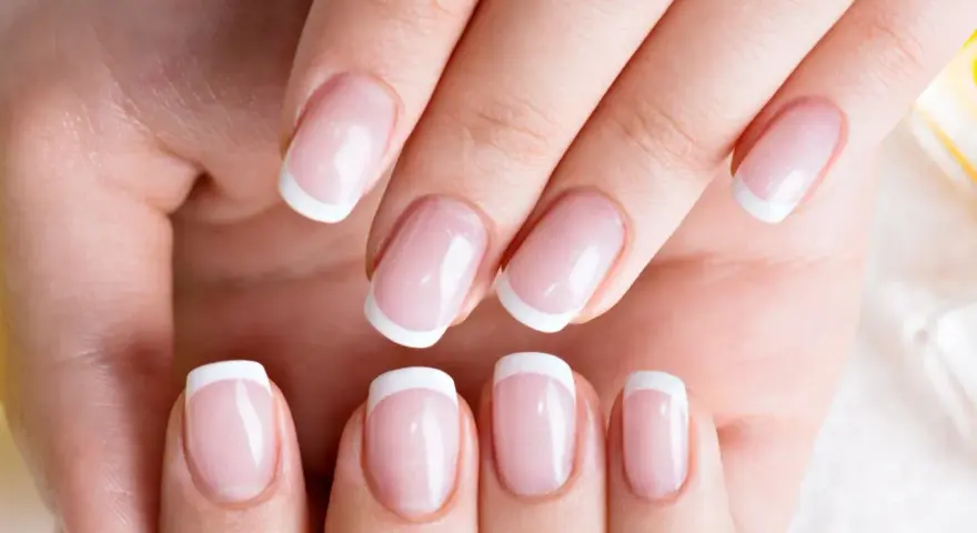 Dłonie z idealnym french manicure, gdzie białe końcówki paznokci lśnią jak tytanowe paznokcie.