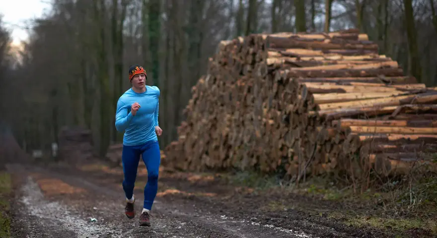 Biegacz w lesie, obok stosu drewna, czerpie siły z czystego powietrza. To jego strefy tlenowe.