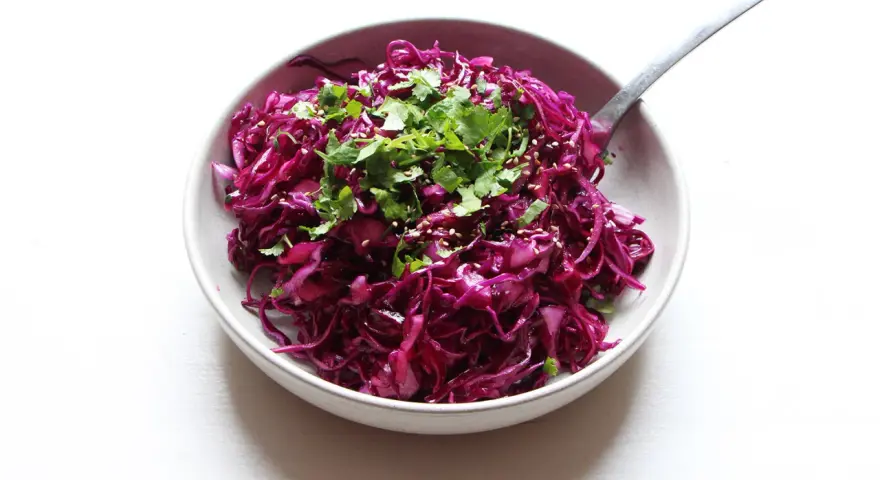 Salade colorée de chou rouge râpé, garnie de coriandre fraîche et de graines de sésame. Une idée simple pour une recette chou rouge savoureuse.