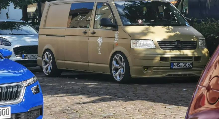 Złoty bus, przeróbka busa na kampera przepisy. Stylowe felgi, naklejki i palma na boku.