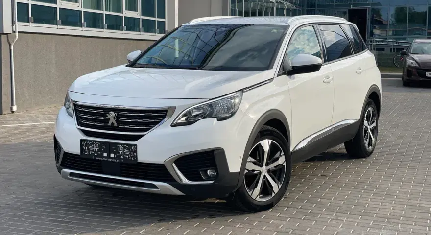 Biały Peugeot 5008 na parkingu. Wiele osób szuka peugeot 5008 opinie, ten SUV to świetny wybór.