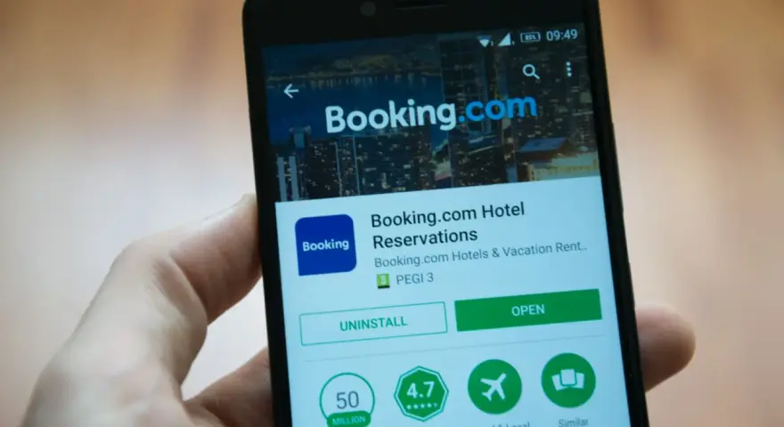 Telefon z aplikacją Booking.com. Użytkownik przegląda szczegóły, być może w celu zgłoszenia booking reklamacja.