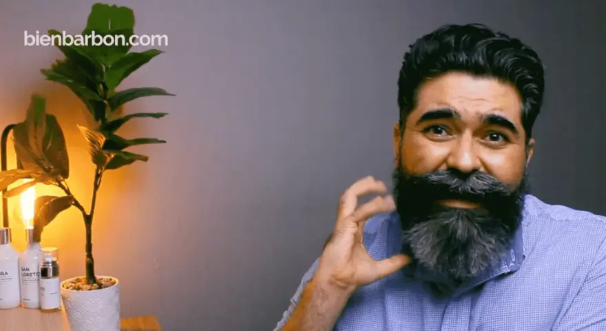 Hombre con una barba corta y cuadrada, peinada con estilo. A su lado, una planta y productos de cuidado personal.