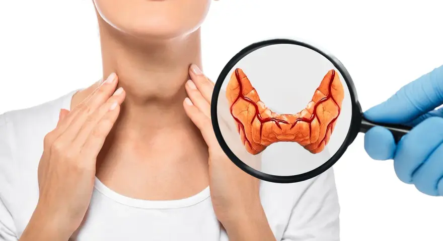 Badanie tarczycy pod kątem guzków. Dłoń kobiety dotyka szyi, a lupa powiększa obraz gruczołu.