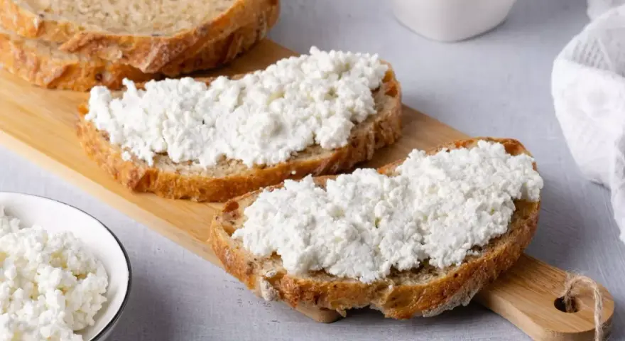 Fette di pane rustico con abbondante ricotta fresca, pronte per gustose ricette con ricotta.