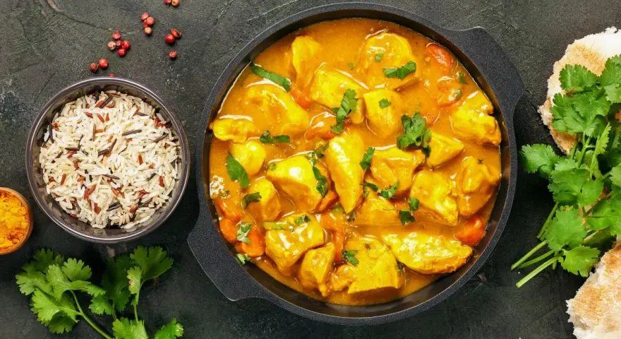 Kurczak w sosie curry z ryżem, kolendrą i pieczywem.