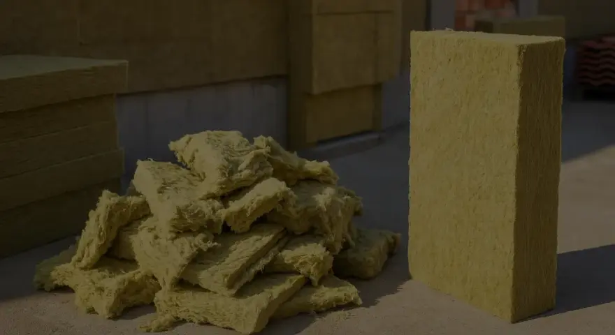 Stos wełny mineralnej i pojedynczy blok, gotowe do utylizacji. Materiał izolacyjny czeka na właściwe zagospodarowanie.