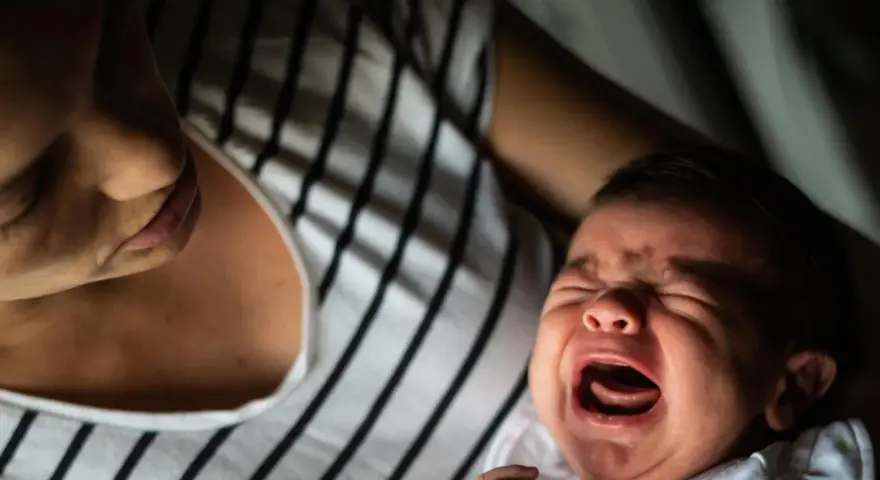 Ein schreiendes Baby, das von seiner Mutter getröstet wird. Vielleicht ein Zeichen für eine frühe Hochbegabung, die sich in intensiven Emotionen äußert.