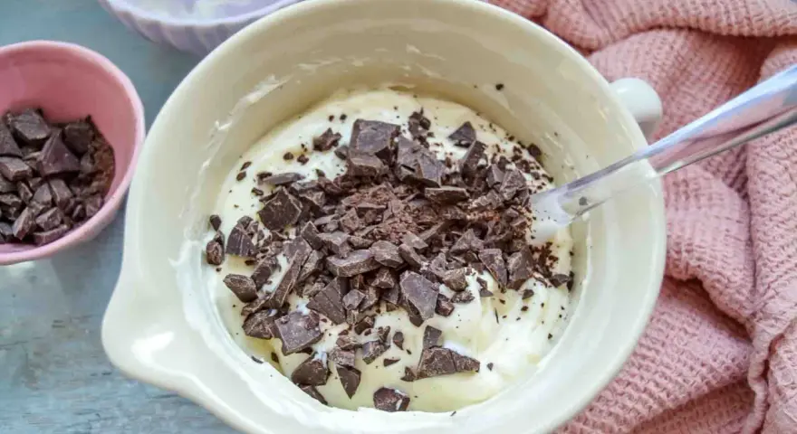 Cremige Masse mit Schokoladenstückchen, bereit für das Herrencreme Rezept. Kleine Schale mit gehackter Schokolade daneben.