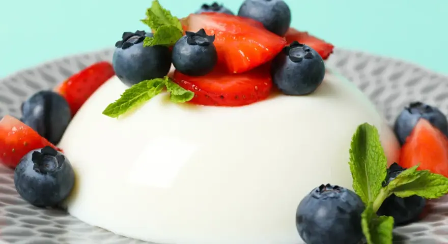 Szybkie ciasto z 4 składników: panna cotta z jagodami i truskawkami, ozdobiona miętą.