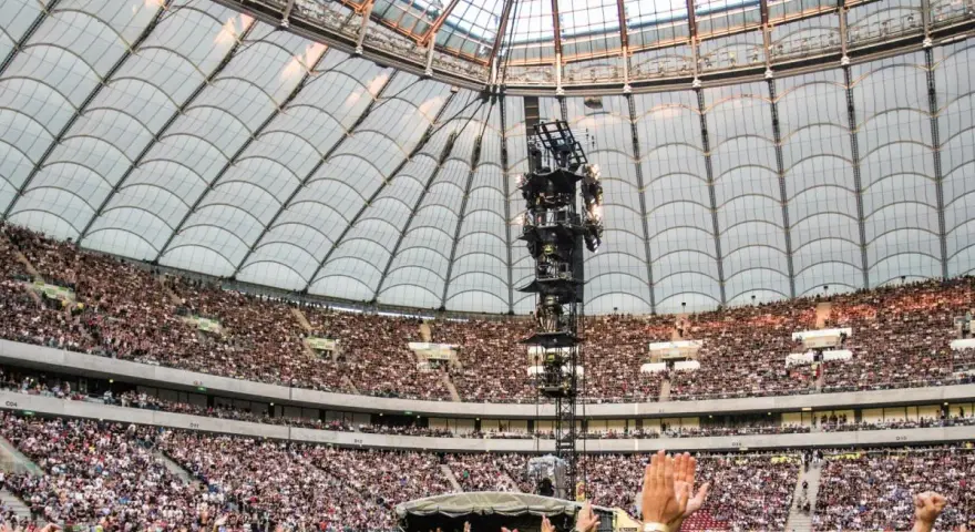 Roztanczony PGE Narodowy w Warszawie, tłumy ludzi na koncercie pod dachem stadionu.
