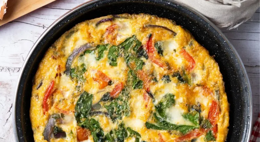 Pyszny omlet z cukinią, pomidorami i szpinakiem, zapieczony w patelni. Idealny na śniadanie lub lekki obiad.