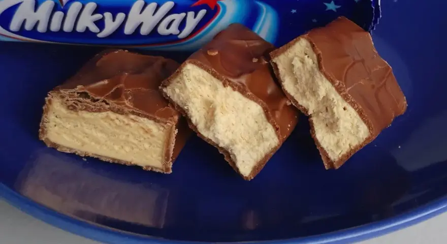 Czekoladowe batoniki Milky Way na niebieskim talerzu. Zastanawiasz się, ile kalorii ma Milky Way?