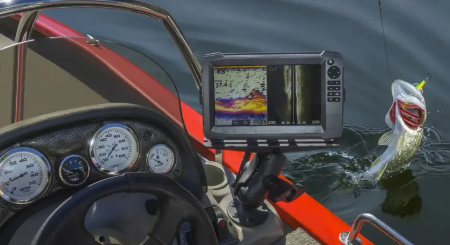 Ein Fisch springt aus dem Wasser, während das Echolot Bild Fische anzeigt.
