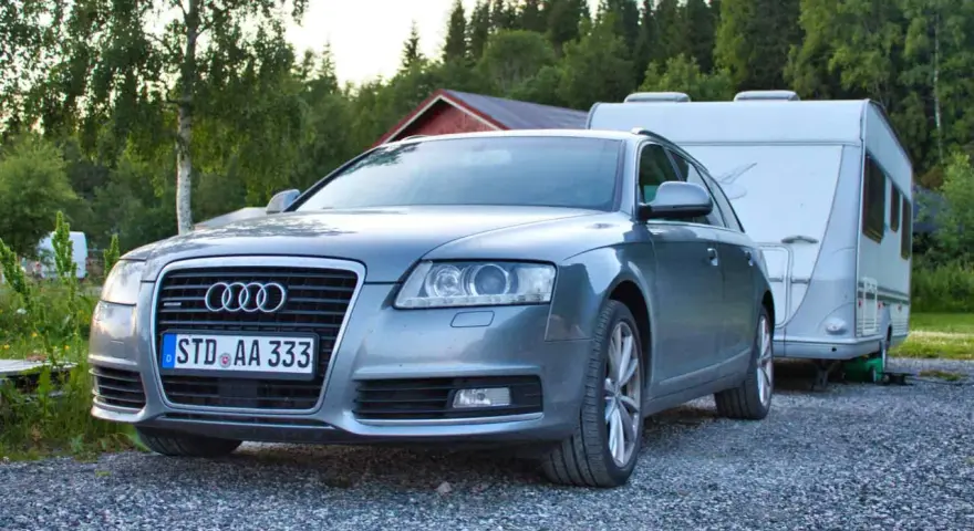 Grauer Audi A6 F4 Kombi mit Wohnwagen im Hintergrund, bereit für den Urlaub.