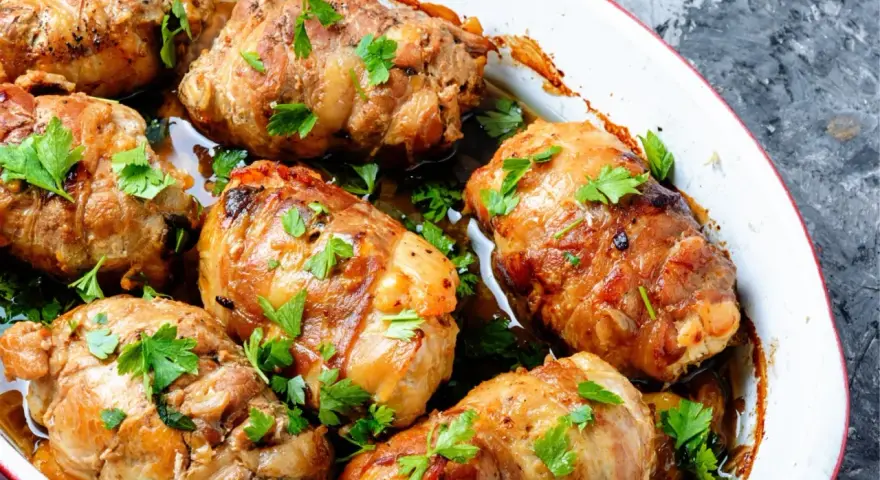 Involtini di carne dorati e succulenti, guarniti con prezzemolo fresco, cotti in una teglia bianca.