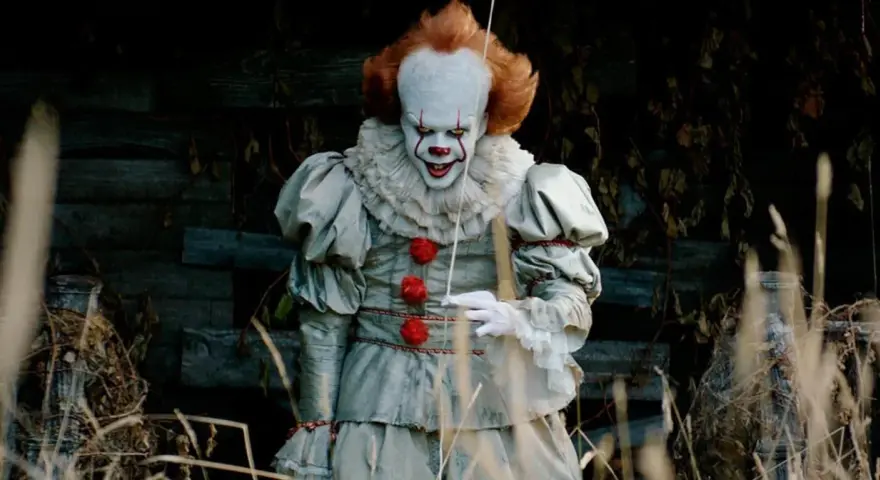 Przerażający klaun Pennywise, znany z horrorów Netflix, wychodzi z mroku.
