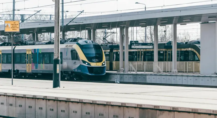 Nowoczesny pociąg Małopolska na stacji. Uważaj na znaki ostrzegawcze, by uniknąć opłaty manipulacyjnej i niebezpieczeństwa.