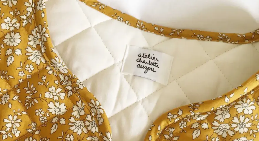 Détail d'une veste matelassée femme avec un tissu fleuri jaune moutarde. Un patron gratuit pour créer ce modèle est disponible.
