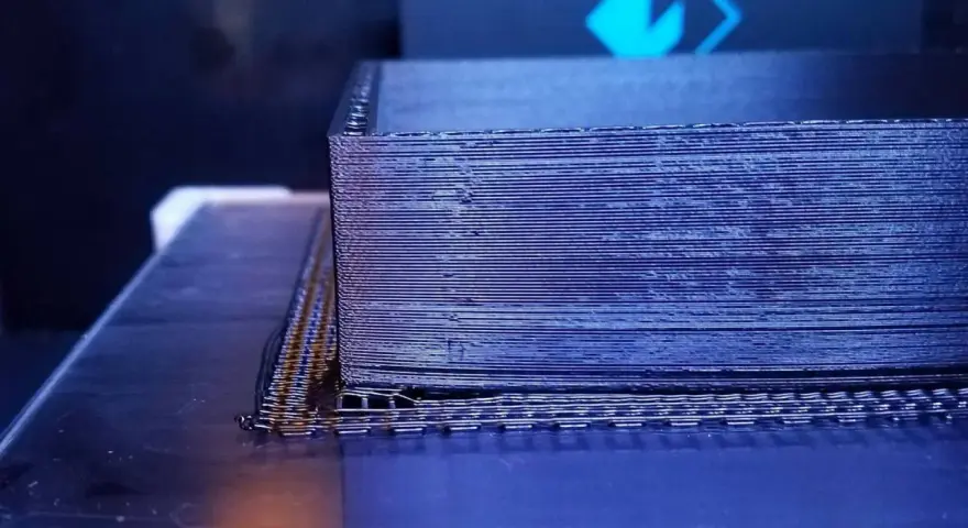 Drukarka 3D tworzy obiekt z czarnego materiału PEEK, warstwa po warstwie.