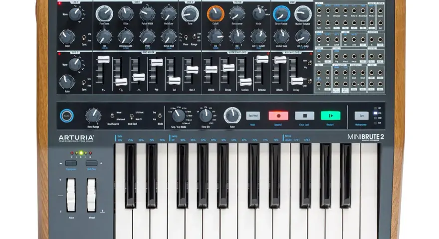 MiniBrute 2, syntezator analogowy z drewnianymi panelami bocznymi, oferuje bogactwo dźwięków wytwarzanych przez oscylator, z licznymi pokrętłami i suwakami do modulacji.