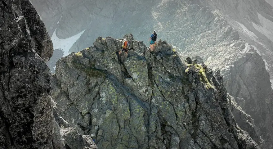 Dwóch alpinistów pokonuje skalisty grzbiet. Jeden z nich zjeżdża na linie, drugi czeka na szczycie. To trudna droga Martina na Gerlach.