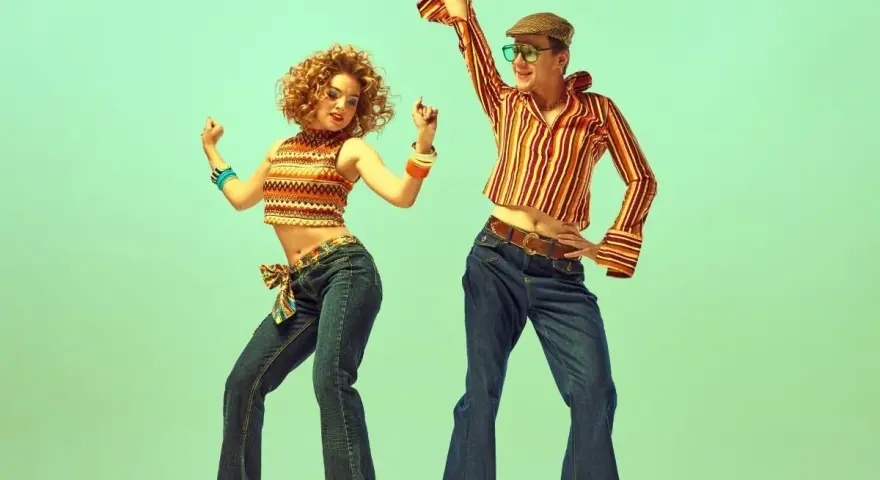 Para tańczy w rytm disco, ubrana w stylowe dzwony i wzorzyste topy, uosabiając modę lat 70.