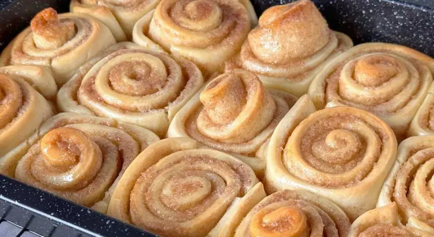 Frisch gebackene Zimtschnecken im Blech, bereit für das Zimtschnecken Rezept. Goldbraun und duftend, ein Genuss!