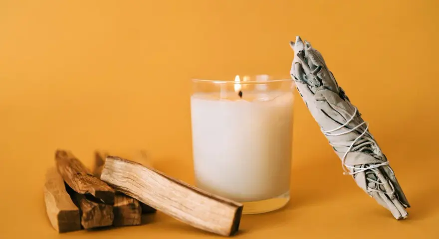 Palosanto, vela encendida y manojo de salvia. Prepara tu espacio para como quemar palo santo y purificar el ambiente.