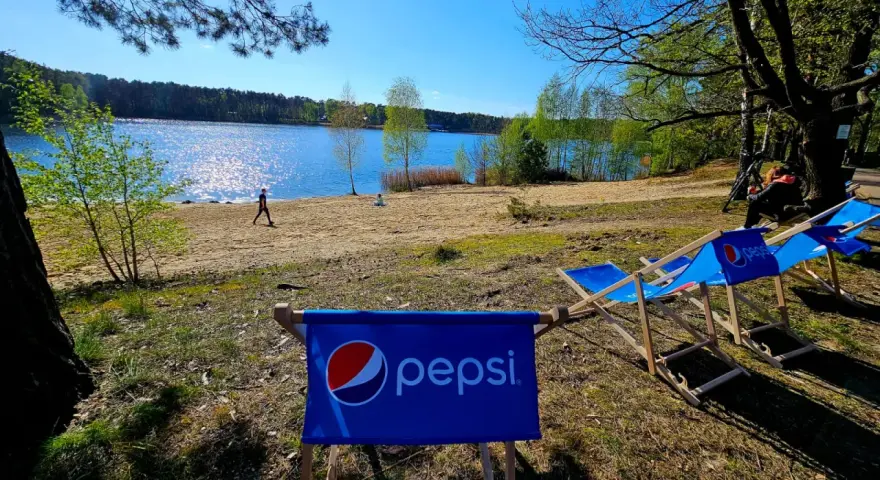 Słoneczny dzień nad jeziorem, leżaki z logo Pepsi czekają na gości turawa camp.