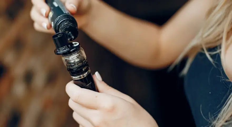 Manos rellenando un cigarrillo electrónico, mostrando las tecnologías sub ohm para una experiencia de vapeo intensa.