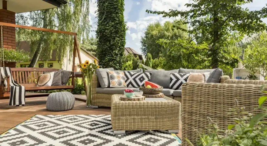 Relaks na tarasie w stylu boho: wiklinowe meble, huśtawka, wzorzysty dywan i mnóstwo zieleni.