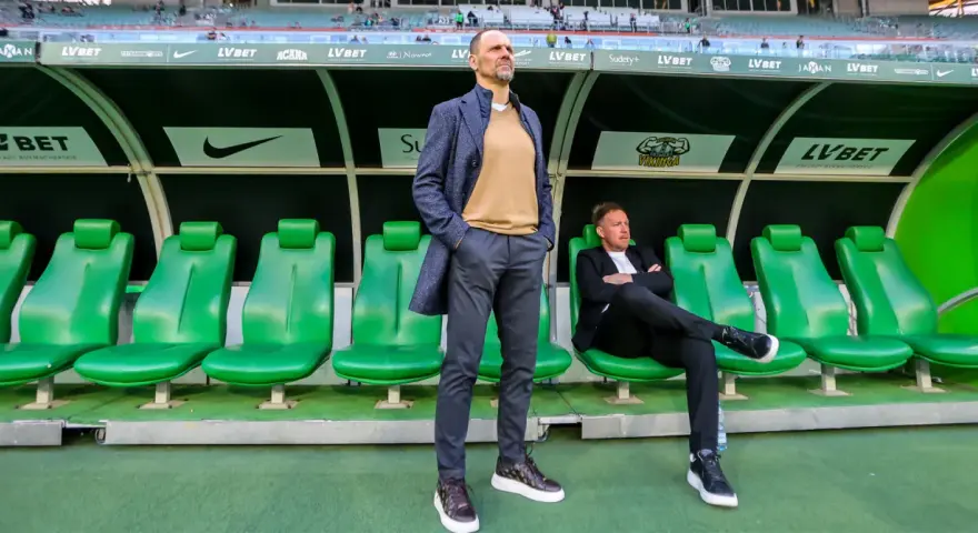 Trener Śląska Wrocław Ivan Djurdjevic stoi na tle zielonych siedzeń rezerwowych.