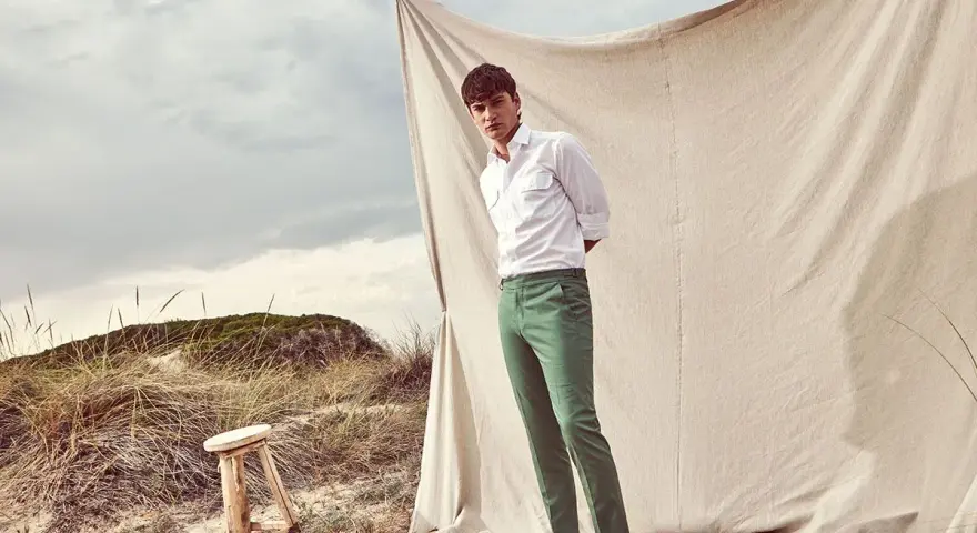 Un uomo con camicia bianca e pantalone verde, un look perfetto per l'estate. Scopri come abbinare un pantalone verde per un outfit fresco e alla moda.