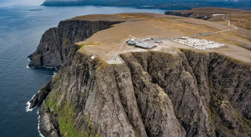 Majestatyczne klify na Nord Kapp, z widokiem na ocean i budynkami turystycznymi.