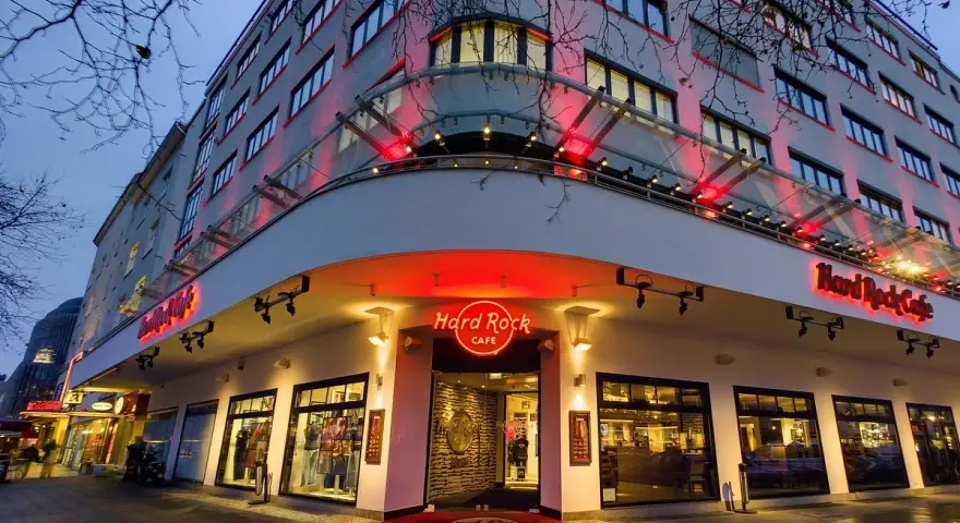 Das Hard Rock Cafe Berlin erstrahlt im Abendlicht. Rote Neonschilder und Beleuchtung werfen einen warmen Schein auf die Fassade des Gebäudes.