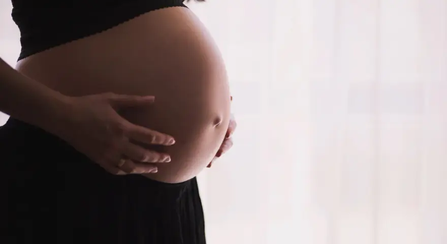 Gravid mage med händer som varsamt håller om den. Kanske funderar hon på proteinpulver gravid för att ge extra näring.