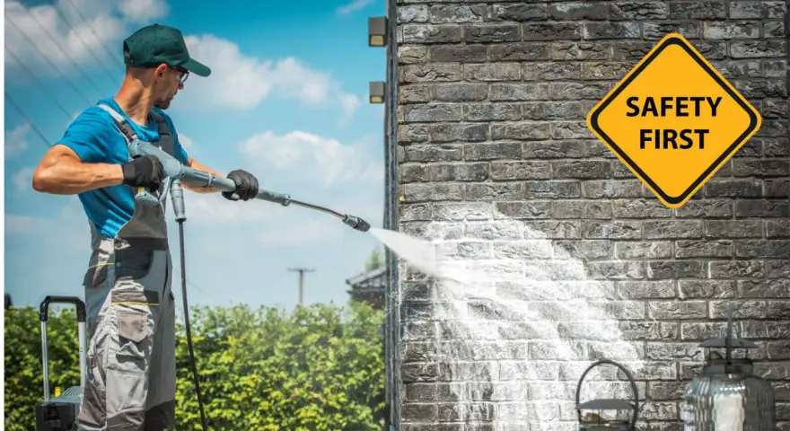 Man demonstrates how to use a pressure washer on a brick wall, with a "Safety First" sign visible.